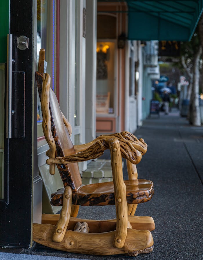 A detailed view of a handmade wooden chair displayed on a city sidewalk, showcasing craftsmanship.