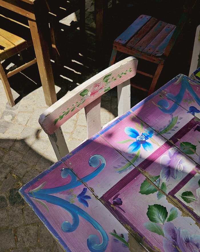 Vibrant hand-painted wooden chair and table set in sunny outdoor patio.